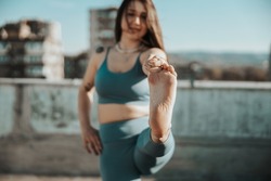 Young woman practicing yoga while doing training outdoors. Selective focus, focus on a woman's foot.