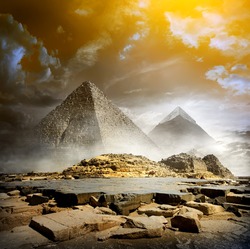 Orange storm clouds and fog over egyptian pyramids