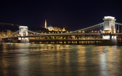Budapest, Hungary. Szechenyi Chain Bridge across Danube, and Matthias Church and Fisherman's Bastion on the Castle hill in night.