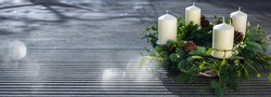 Advent wreath on gray wooden planks with silver bokeh lights. Horizontal christmas background with space for text.