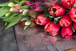 Bunch of fresh colorful tulips on old wooden boards. Spring background for mothers day and easter with space for text.