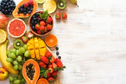 Lots of different fruits, strawberries, blueberries, mango, orange, grapefruit, banana, apple, grapes, kiwis on the white background, copy space for text, selective focus