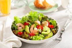 Fresh summer salad with shrimp, avocado and tomato cherry in bowl on light table. Concept of healthy eating.
