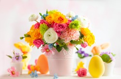 Easter decoration with beautiful spring flowers in vase, Easter eggs and bunny on white wooden table. Festive concept with copy space.