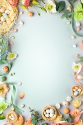 Happy Easter concept with easter eggs in nest and spring flowers. Easter background with copy space. Flat lay.