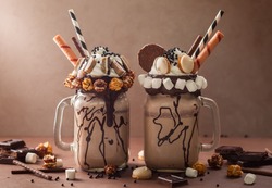 Chocolate  milkshake with ice cream and with whipped cream, marshmallow, sweet popcorn, cookies, waffles, served in glass mason jar. 