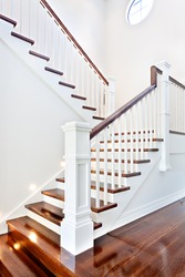Stairs and glossy wooden floor of beautiful attractive luxury house with white walls having round window on top