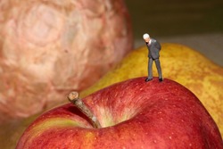 miniature figurine of a businessman on the top of a red apple