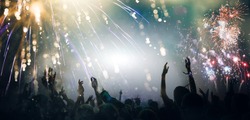 Stage lights and crowd of audience with hands raised at a music festival. Fans enjoying the party vibes. New Years Eve concept. 