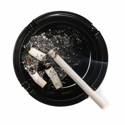 Lit cigarette in black ashtray isolated on white background, top view