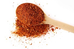 Spicy chili pepper flakes, crushed, milled red paprika pile in wooden spoon isolated on white, top view