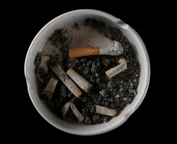 Cigarette stubs, matches and ash in ashtray isolated on white background, top view