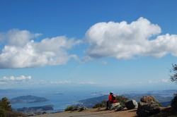Mountain Biker rests near the East Summit of Mt. Tamalpais, California and admires the view of San Francisco Bay