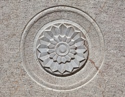 Carved lotus shaped motif on the surface of a gray stone.