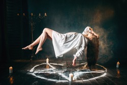 Woman in white shirt flying over pentagram circle