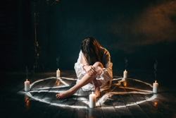 Female person sitting in pentagram circle, magic