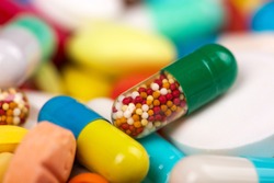 Closeup of medicine capsule against various colorful pills on background