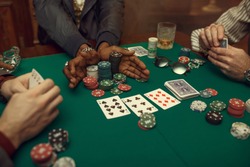 Poker players hands, gaming table on background