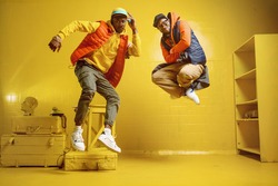 Two stylish rappers in studio, yellow background