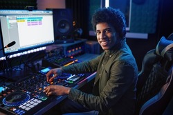 Portrait of radio host using sound mixer in studio
