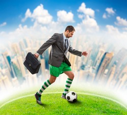 Businessman with suitcase in sportwear playing football in the town