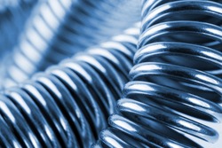 Close-up of coiled metal springs. Toned in blue