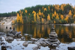 Pyramid of balanced zen stones, yellow and green trees, autumn. Karelia region, Russia