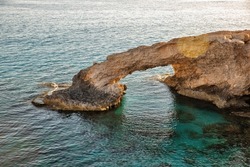 Summer resort rocky coastline seafront view with famous Love Bridge, Cyprus. Beautiful natural rock arch near of Ayia Napa, Mediterranean Sea. Amazing blue green sea and sunny day.