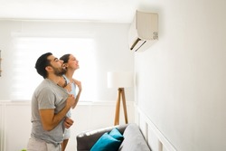 Side view of a relaxed happy woman and man cooling with the cold air flow of the air conditioning 