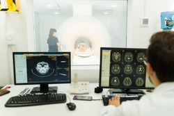 Doctor or radiologist looking at the computer of the brain scan while doing a magnetic resonance on a young woman at the lab
