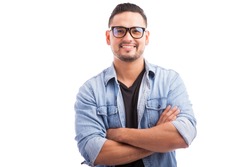 Latin hipster guy wearing glasses with his arms crossed and smiling on a white background