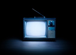 High contrast image of an old vintage TV with white noise on white wood.