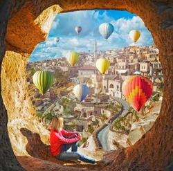Woman watching  like colorful hot air balloons flying over the valley at Cappadocia, Turkey. Volcanic mountains in Goreme national park.