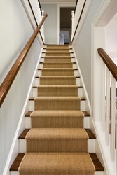 Wide View of wooden staircase with carpet runner and white molding. 