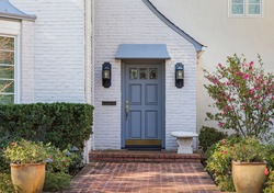 Blue front door of traditional style home with brick entry and white brick exterior.