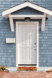 White front door with blue shingle siding of single family home 