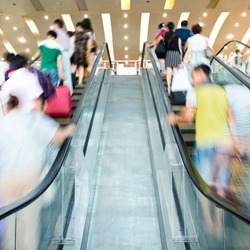 People rush on escalator motion blurred.