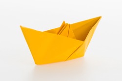 Yellow origami boat on white background.