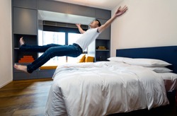 Happy man jumping to the bed.