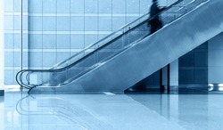 Single business people on escalator, blurred motion