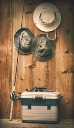 Hats hanging on wooden wall with fishing equipment