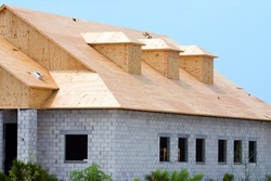 New building under construction showing plywood roof sheeting and three dormers