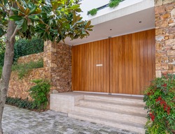 elegant house front huge entrance wooden door and stone fence with green plants