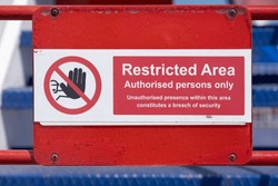 Red and white restricted area sign, authorized persons only, with hand icon, on the deck of a ferry