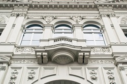 Part of a classic large stone building in London with arches and statues