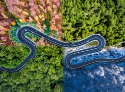 Winding road in all four seasons. Aerial view of a curved highway trough the forest. Composite drone roadway weather image of a hairpin turn