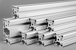 Aluminum exstrusion profile bars on gray background. Metal construction industry engineering and material concept.