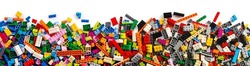 top view of wide pile various mixed colorful rainbow colored stackable plastic toy bricks isolated on white panorama background.. childhood education construction concept