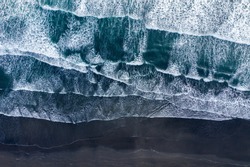 Aerial drone view of Atlantic ocean waves washing black basaltic sand beach, Iceland
