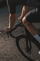 Crop of cyclist's handlebars and front wheel during sunrise
